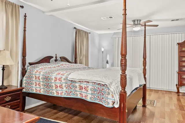 a bedroom with a bed and a dresser with wooden floor