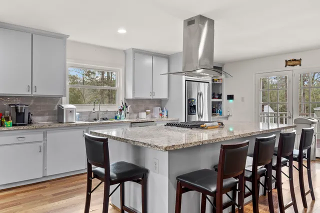 a kitchen with stainless steel appliances granite countertop a stove two chairs and a refrigerator