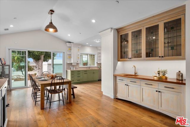 a kitchen with stainless steel appliances kitchen island granite countertop a dining table chairs and white cabinets