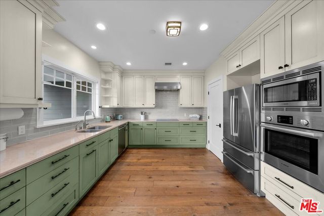 a large kitchen with stainless steel appliances double cabinets and a stove top oven