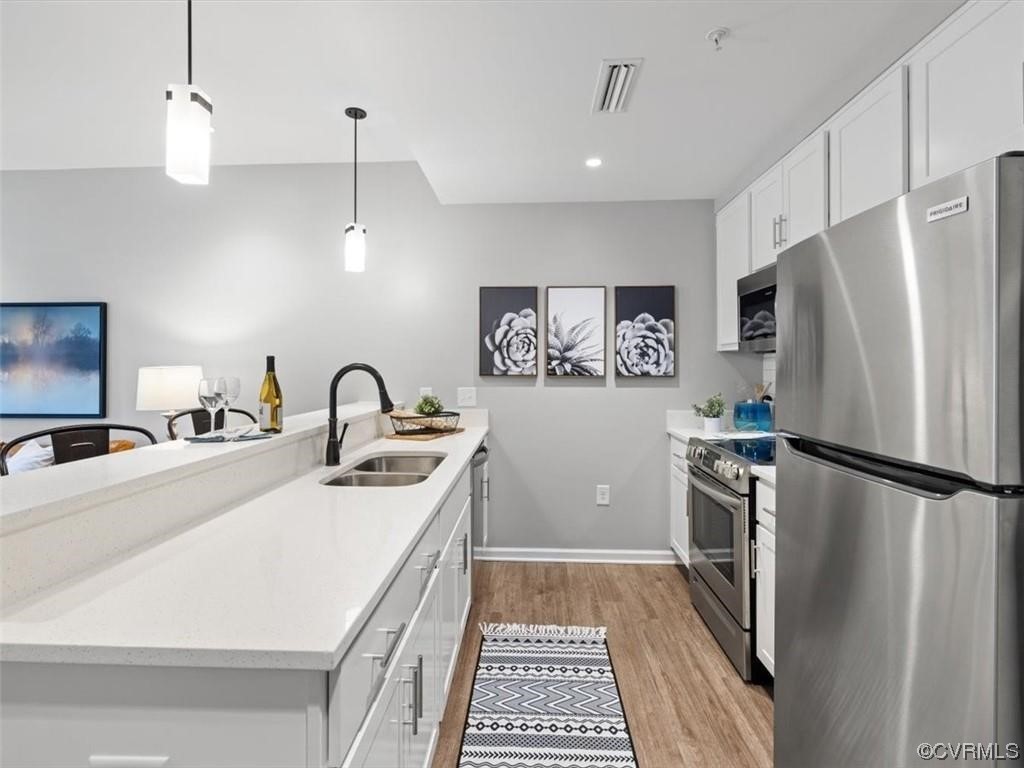 1504 Ewing Park Loop, Unit 206 Midlothian, VA 23113 - Photo 3 of 26 a kitchen with stainless steel appliances a refrigerator sink and wooden floor
