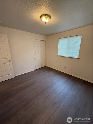 a view of an empty room with wooden floor and a painting on the wall