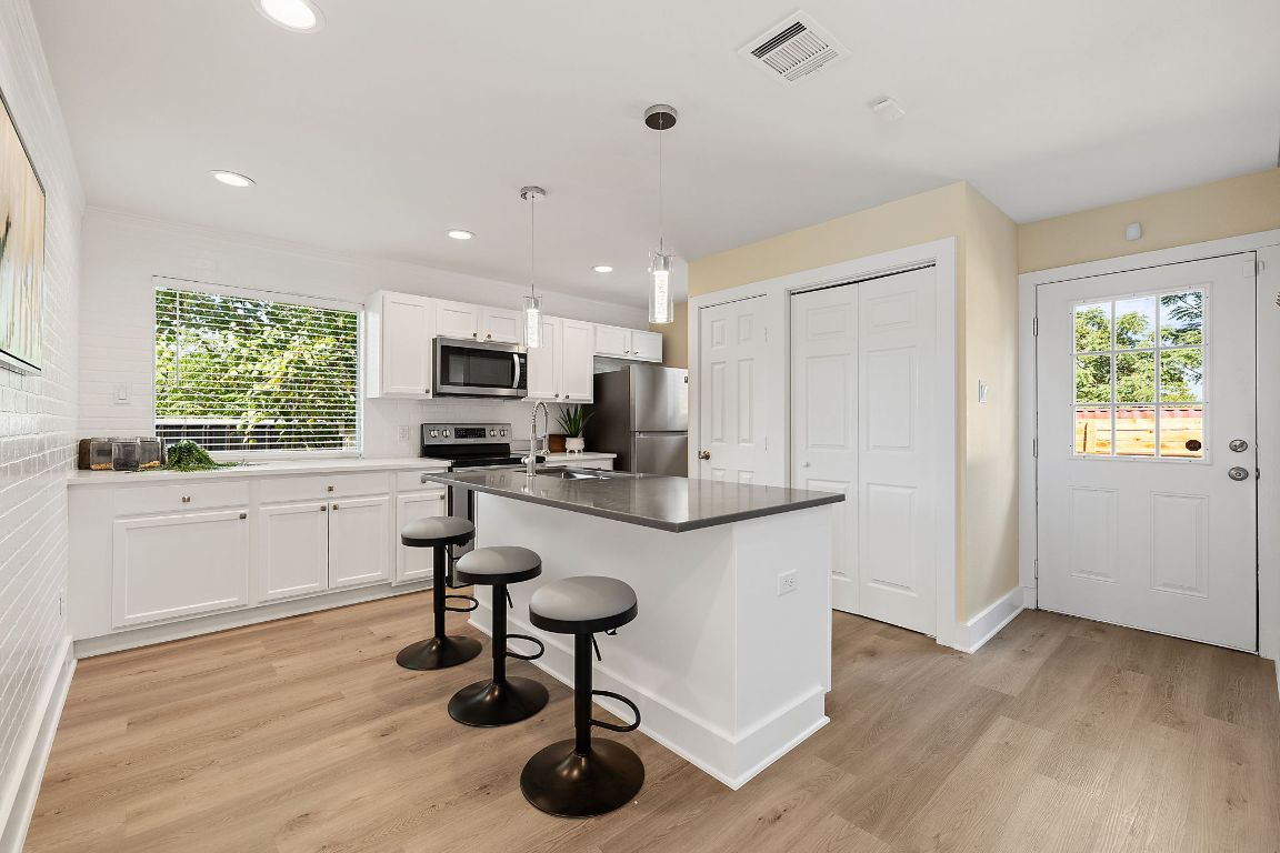 1171 Nickols Avenue, Unit 1 Austin, TX 78721 - Photo 8 of 22 Kitchen with white cabinetry, a kitchen breakfast bar, pendant lighting, a kitchen island, and light wood finished floors