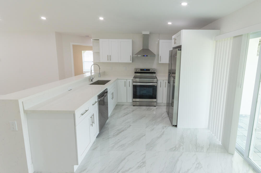 6465 Alexander Road West Palm Beach, FL 33413 - Photo 9 of 20 a kitchen with stainless steel appliances a refrigerator sink and stove