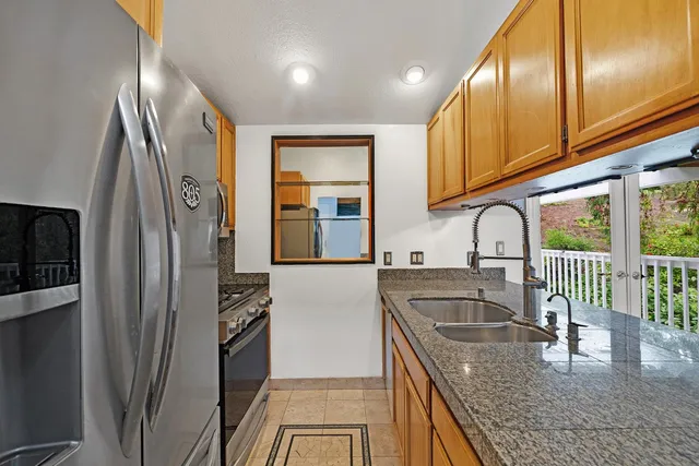 a kitchen with stainless steel appliances granite countertop a refrigerator a sink and a stove