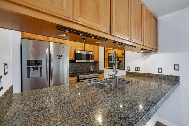 a kitchen with stainless steel appliances granite countertop a sink a stove and refrigerator