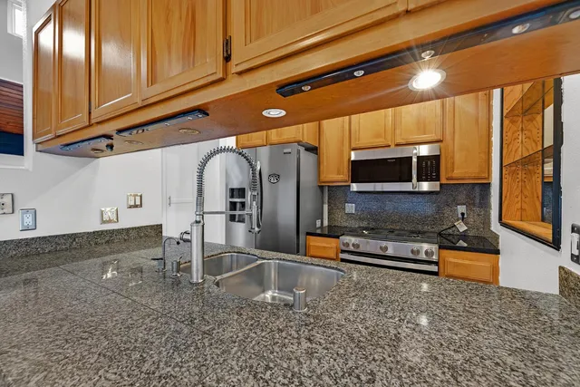 a kitchen with stainless steel appliances granite countertop a refrigerator a stove and cabinets