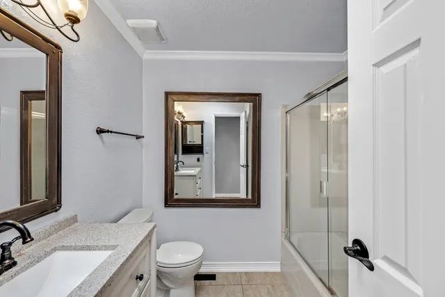 a bathroom with a granite countertop sink vanity mirror and toilet