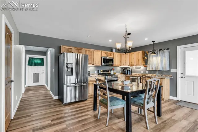 a kitchen with stainless steel appliances a dining table chairs stove refrigerator and cabinets