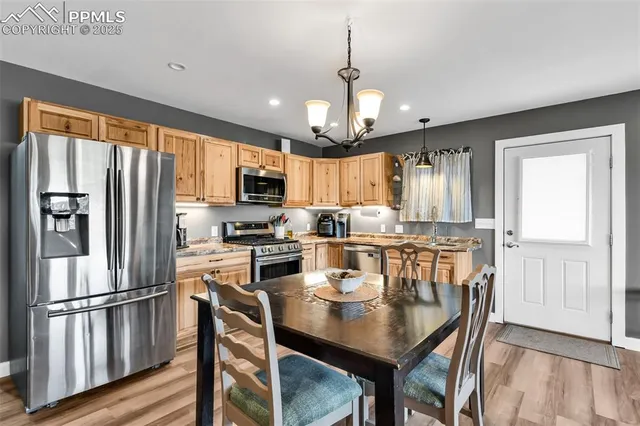 a kitchen with granite countertop a refrigerator a stove a sink dishwasher a dining table and chairs with wooden floor