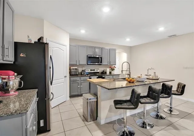 a kitchen with a sink a refrigerator and chairs