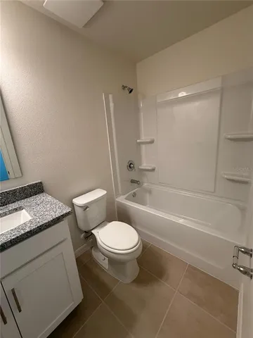 a bathroom with a granite countertop toilet a sink and a bathtub