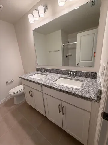 a bathroom with a granite countertop sink a toilet and a mirror