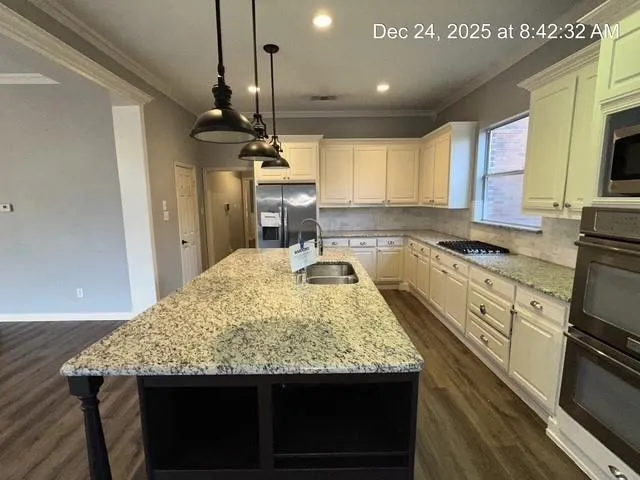 a kitchen with granite countertop kitchen island stainless steel appliances a sink stove and cabinets