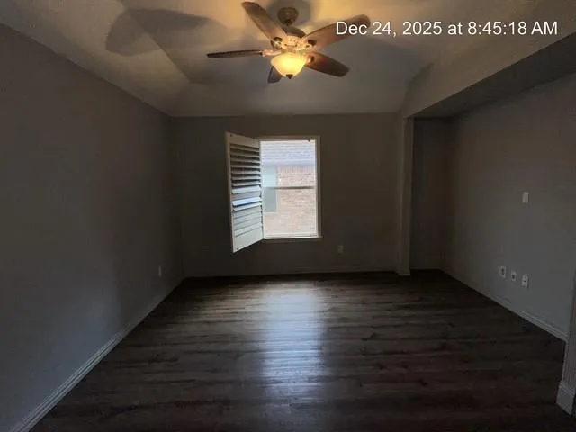 a view of an empty room with window and wooden floor