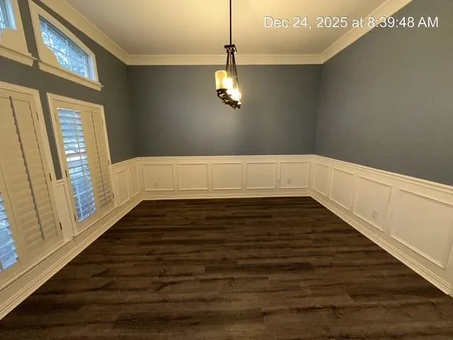 a view of an empty room with wooden floor and windows