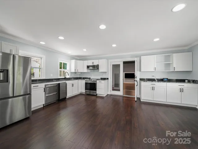 a kitchen with stainless steel appliances wooden floors and view living room