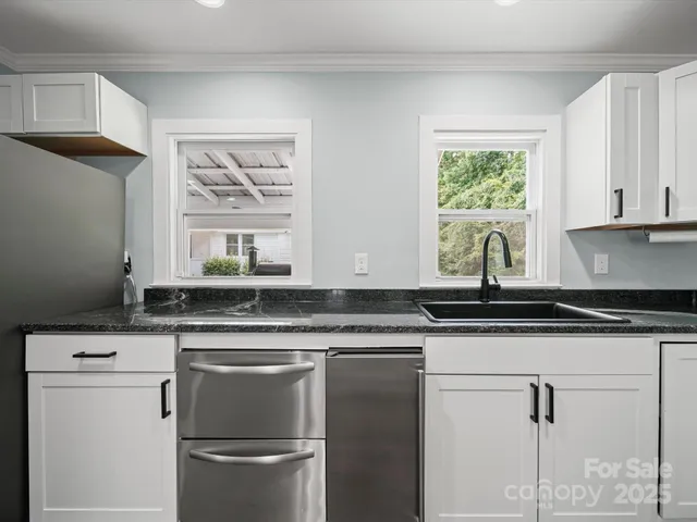 a kitchen with granite countertop a sink stainless steel appliances and white cabinets