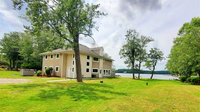 a view of a house with a big yard and large trees