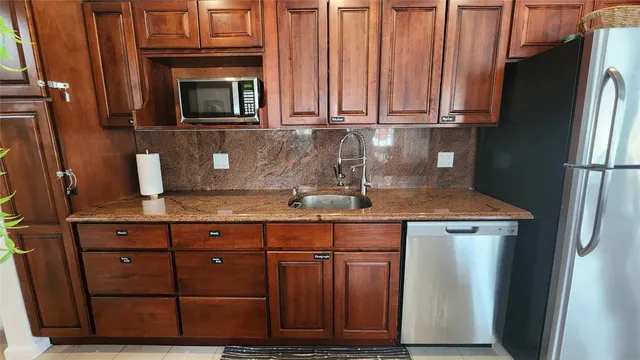 a kitchen with stainless steel appliances granite countertop a refrigerator and a stove top oven