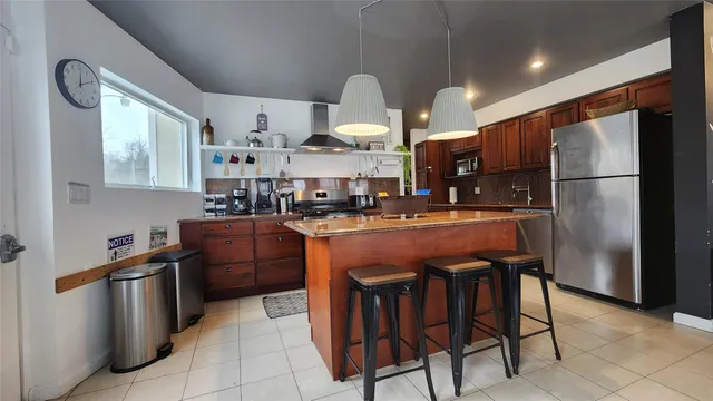 a kitchen with stainless steel appliances granite countertop a sink a stove a refrigerator and island with wooden floor