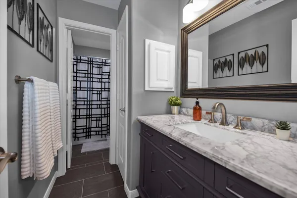 a bathroom with a granite countertop sink a mirror and shower