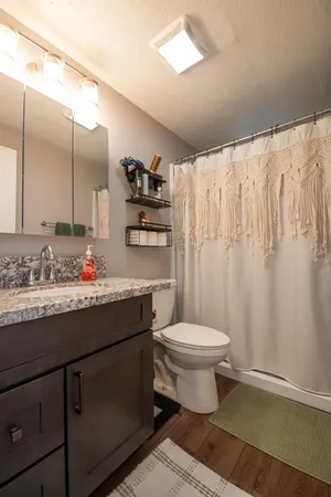 a bathroom with a granite countertop sink toilet and a mirror