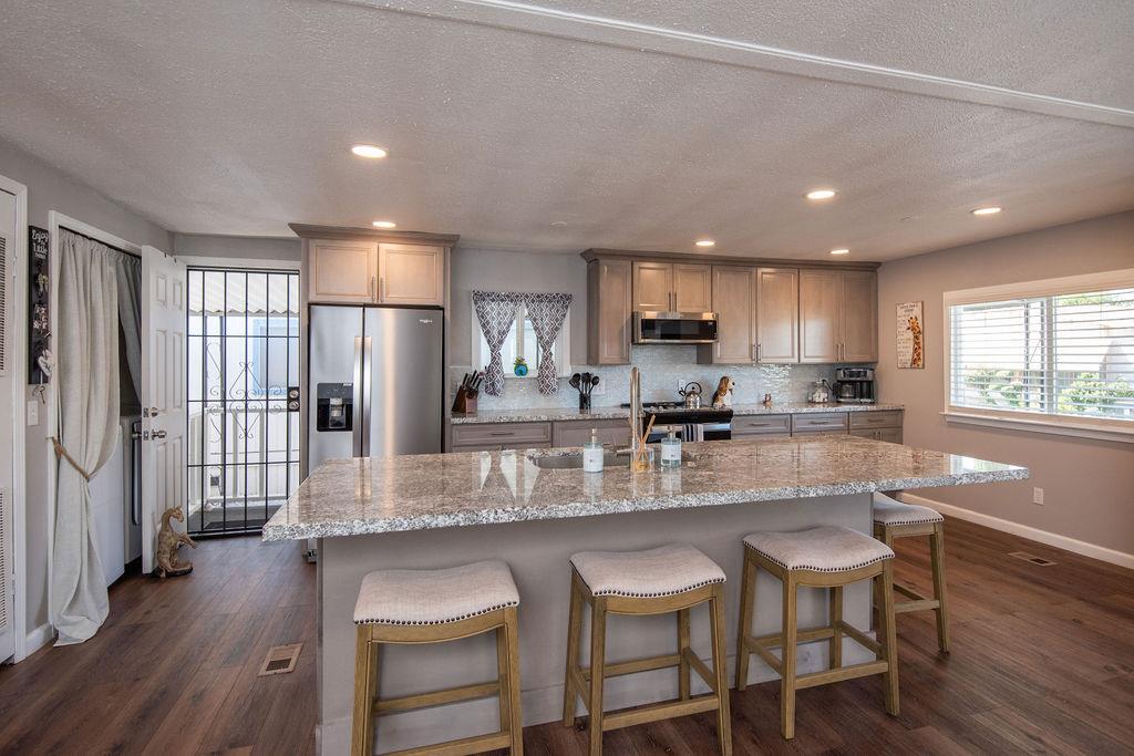 107 Schooner Lane Modesto, CA 95356 - Photo 6 of 43 a kitchen with stainless steel appliances granite countertop a refrigerator a sink dishwasher a stove and white cabinets with wooden floor