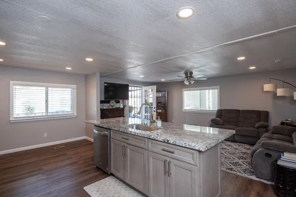 a kitchen with granite countertop a sink cabinets and wooden floor