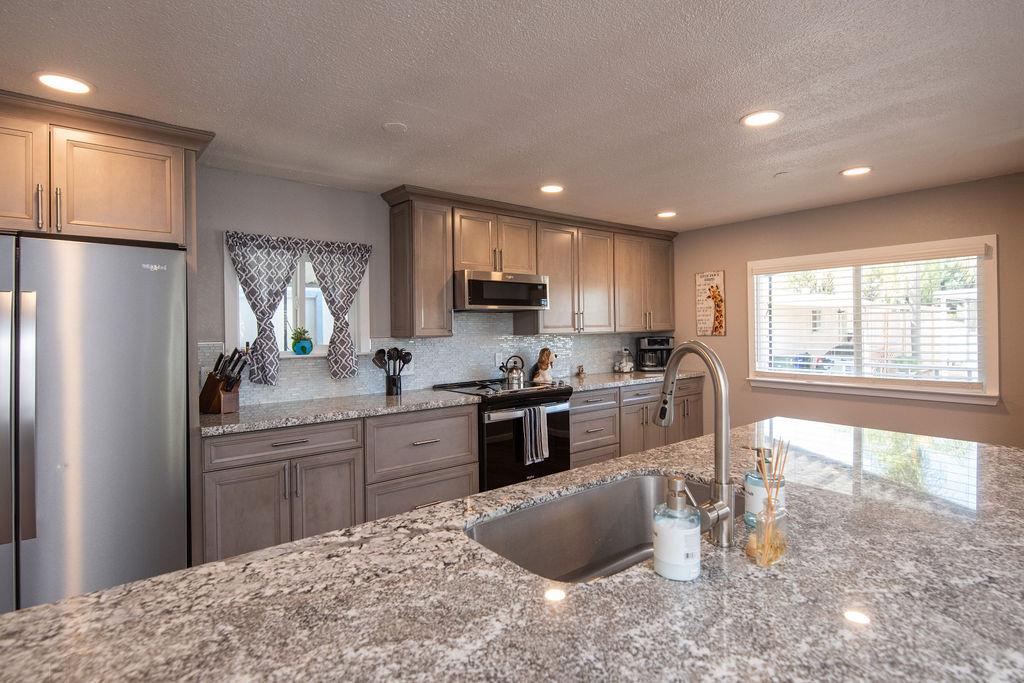 107 Schooner Lane Modesto, CA 95356 - Photo 10 of 43 a kitchen with stainless steel appliances granite countertop a refrigerator sink and stove