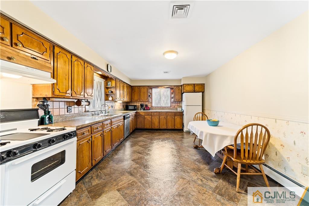 39 Landvale Road Spotswood, NJ 08884 - Photo 8 of 34 a kitchen with a table chairs stove and cabinets