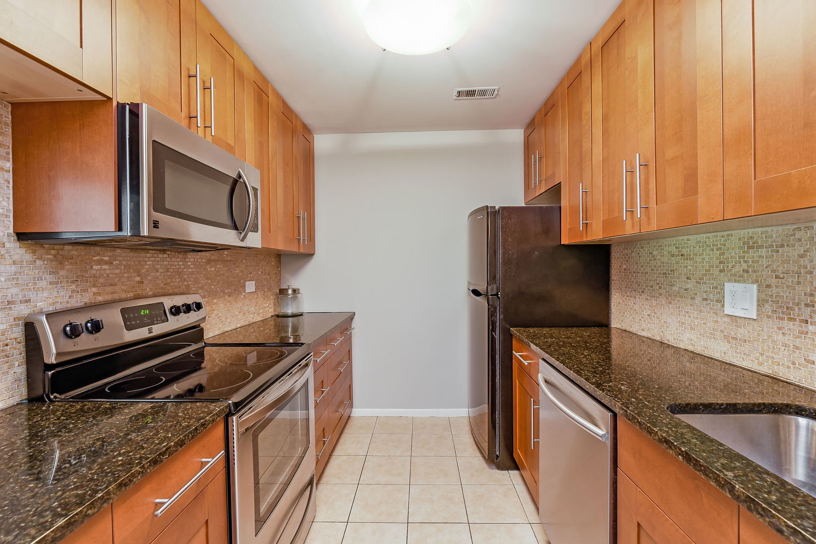 1464 Stonebridge Circle, Unit E3 Wheaton, IL 60189 - Photo 3 of 9 a kitchen with stainless steel appliances granite countertop a stove a sink and a microwave