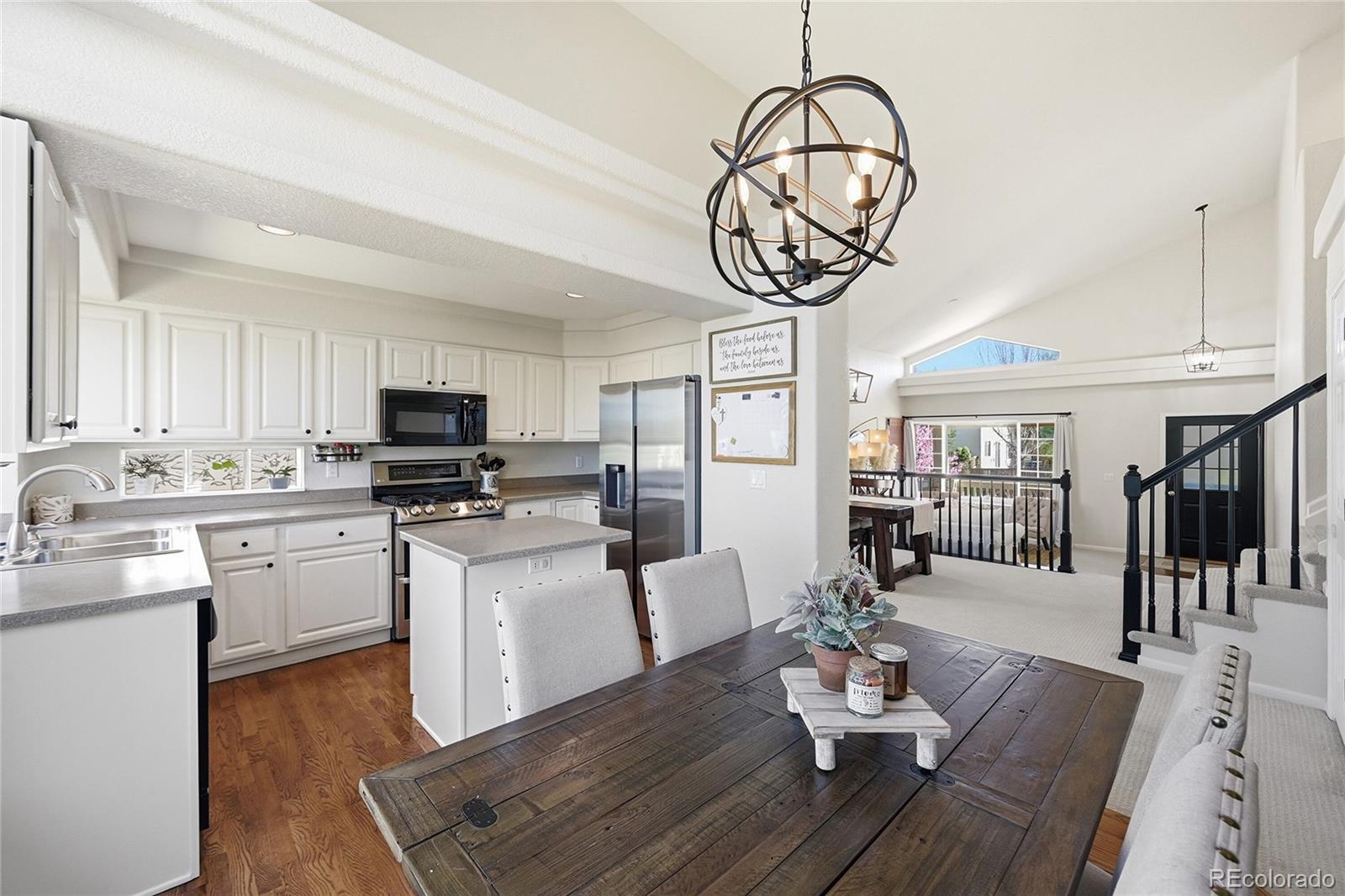 9153 Roadrunner Drive Highlands Ranch, CO 80129 - Photo 12 of 39 a open kitchen with stainless steel appliances granite countertop a stove and white cabinets with wooden floor