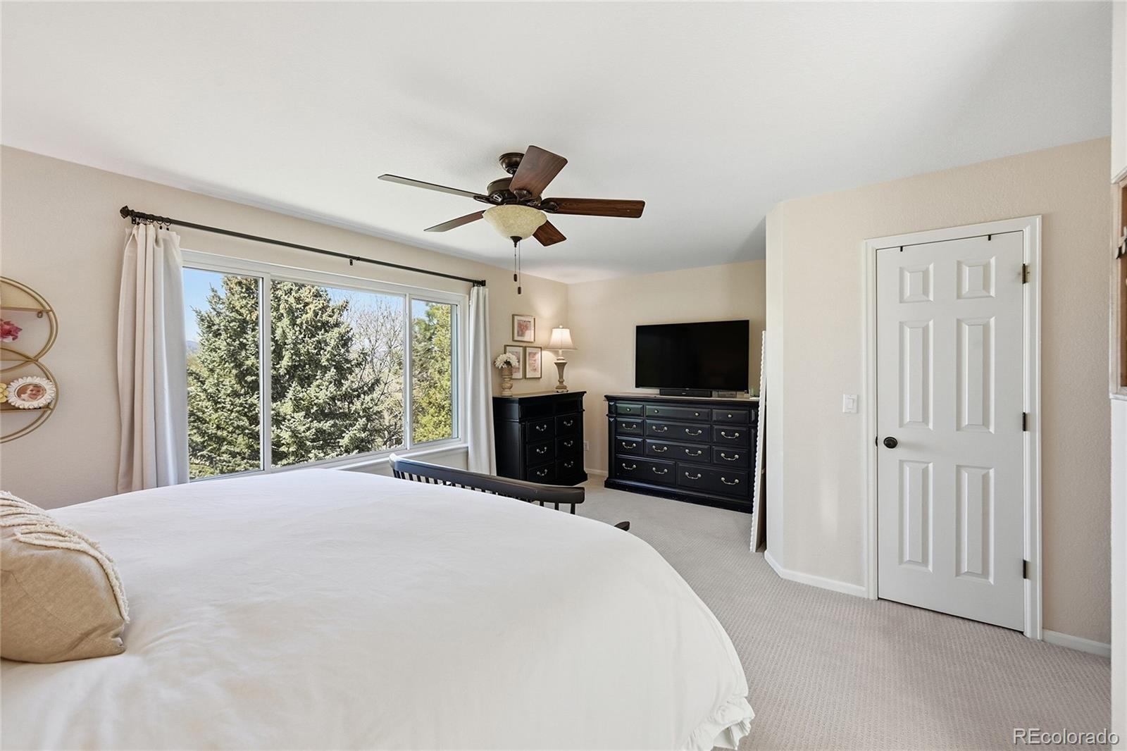 9153 Roadrunner Drive Highlands Ranch, CO 80129 - Photo 21 of 39 a large bedroom with a bed and a flat screen tv