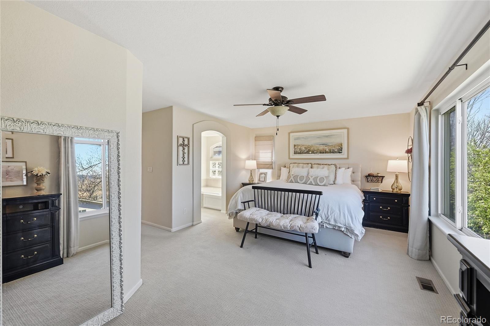 9153 Roadrunner Drive Highlands Ranch, CO 80129 - Photo 22 of 39 a spacious bedroom with a bed and a chandelier