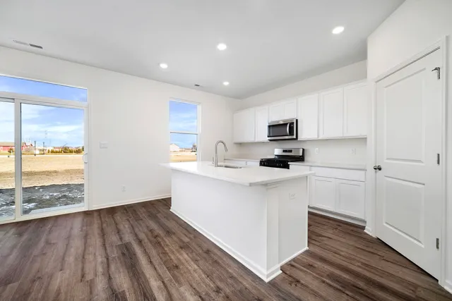 a kitchen with a hard wood floor white cabinets and wooden floor