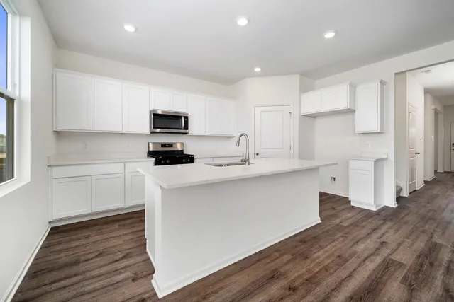 a kitchen with stainless steel appliances white cabinets a sink a stove a refrigerator and a microwave