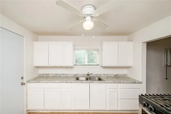 a kitchen with granite countertop a stove a sink and dishwasher with white cabinets