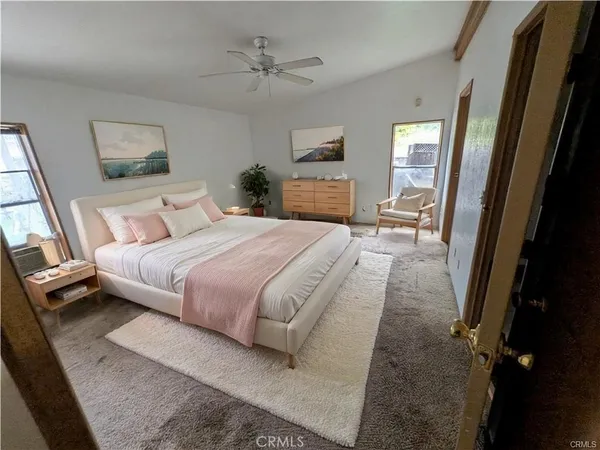 a bedroom with a bed a mirror on dresser and a window