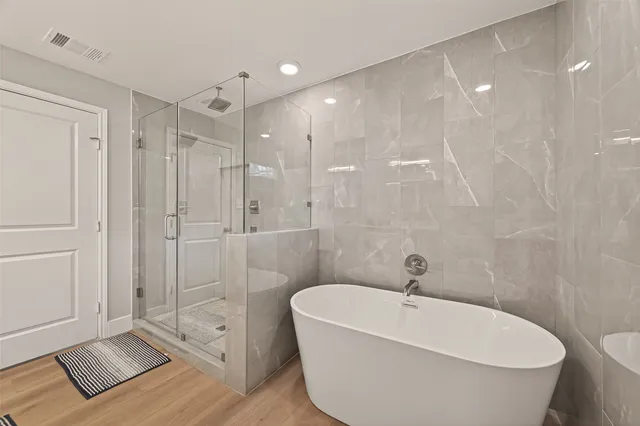 a bathroom with a white bath tub a shower and a sink