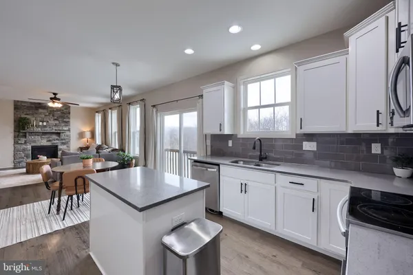 an open kitchen with granite countertop a stove and white cabinets
