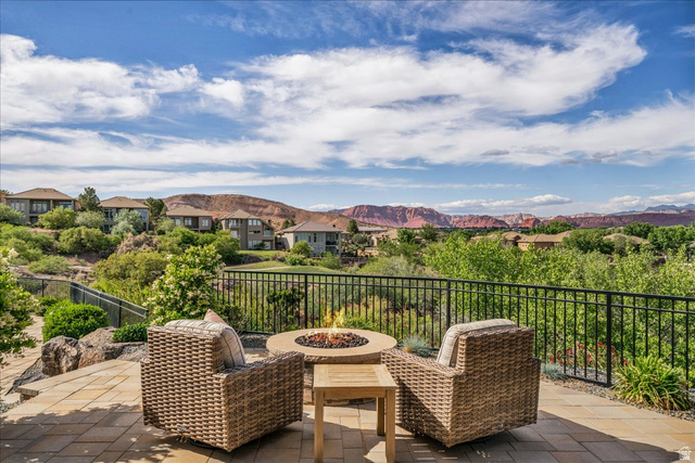 2608 Canyon Ridge Drive St. George, UT 84770 - Photo 78 of 86 Expansive outdoor patio featuring a paver stone surface, a built-in fire pit, and a black metal railing