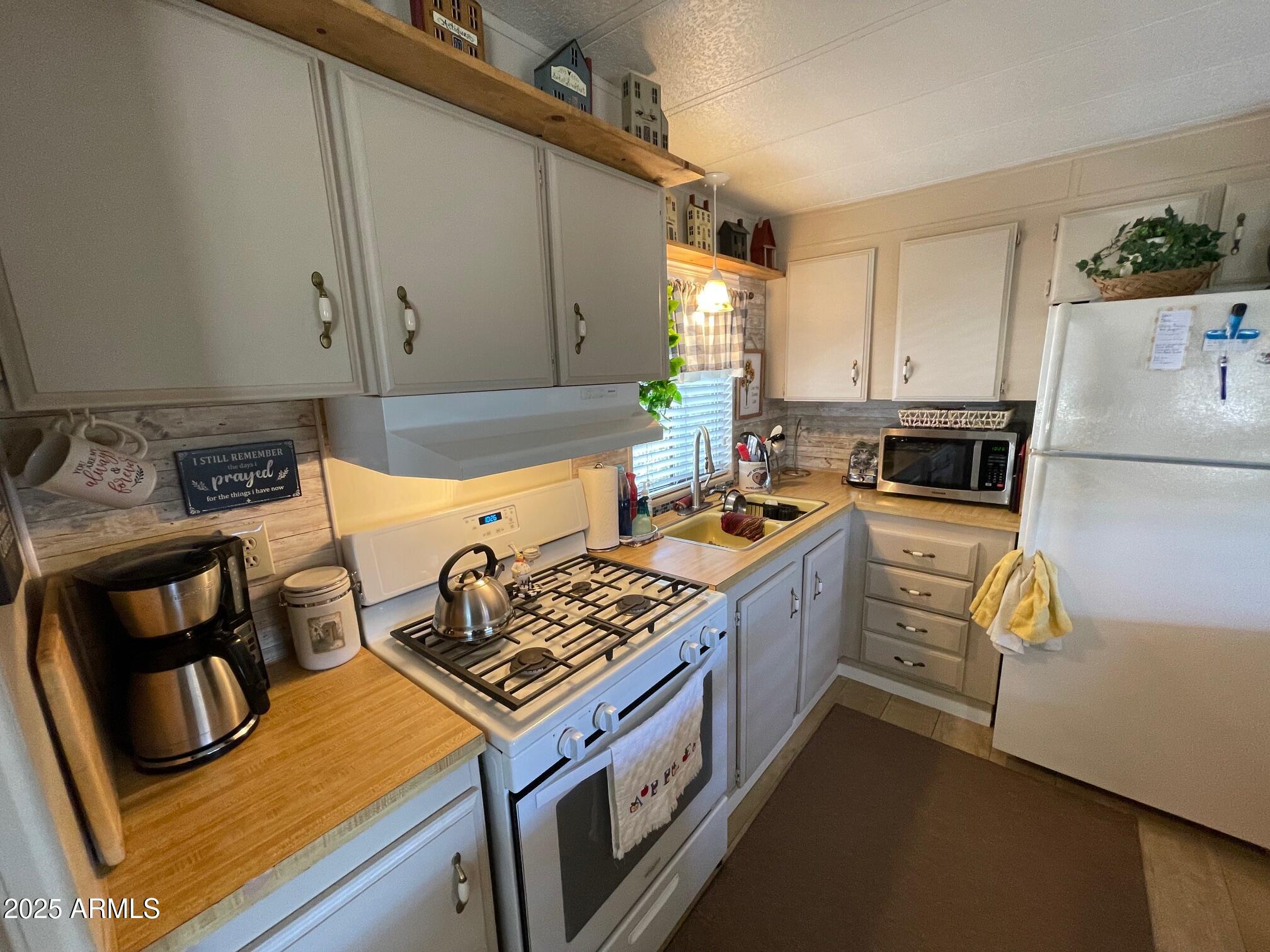 980 East Broadway Avenue, Unit 15 Apache Junction, AZ 85119 - Photo 10 of 24 a kitchen with stainless steel appliances granite countertop a stove a sink dishwasher and a refrigerator