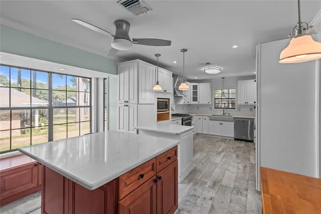 a kitchen with stainless steel appliances kitchen island granite countertop a stove a oven and a white cabinets with wooden floor