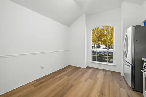 a view of a room with wooden floor and a refrigerator