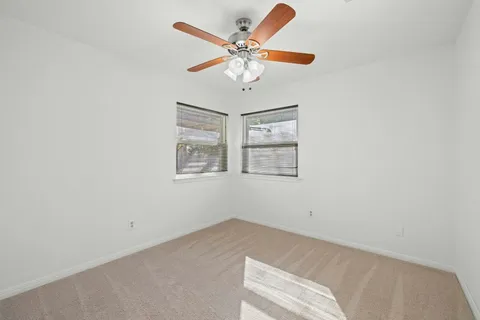 an empty room with windows and ceiling fan