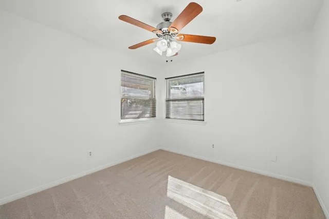 an empty room with windows and ceiling fan