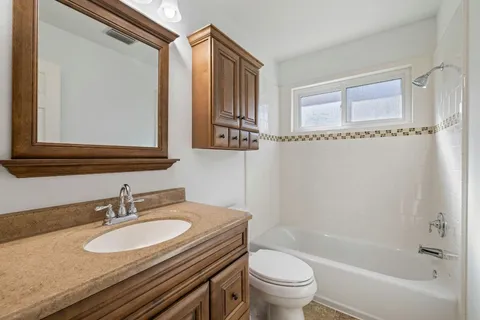 a bathroom with a granite countertop sink toilet a mirror and shower