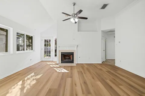 a view of a livingroom with a fireplace a ceiling fan and wooden floor
