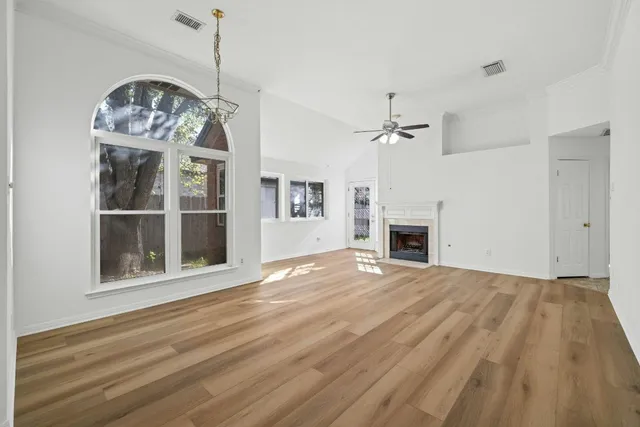 a view of a livingroom with a fireplace a chandelier a wooden floor and windows